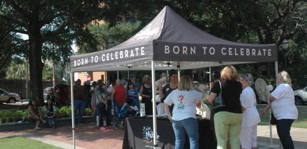 people crowded around a Visit Mobile table under a tent