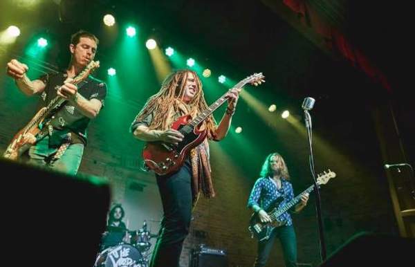 three men on stage playing guitar and singing