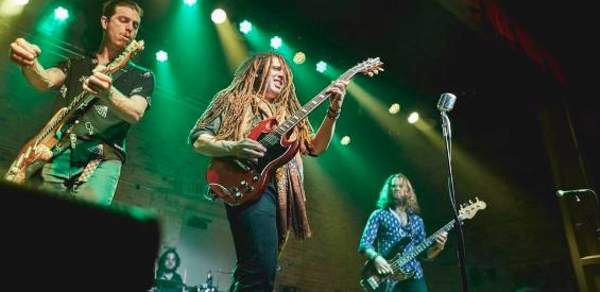 three men on stage playing guitar and singing