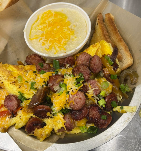 Omelet on a plate with sausage, cheese, green onions, toast and grits topped with cheese