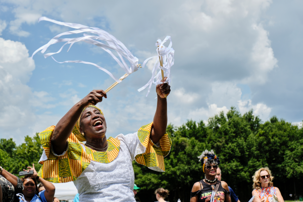 African American woman in traditional dress waving ribbons in the sky